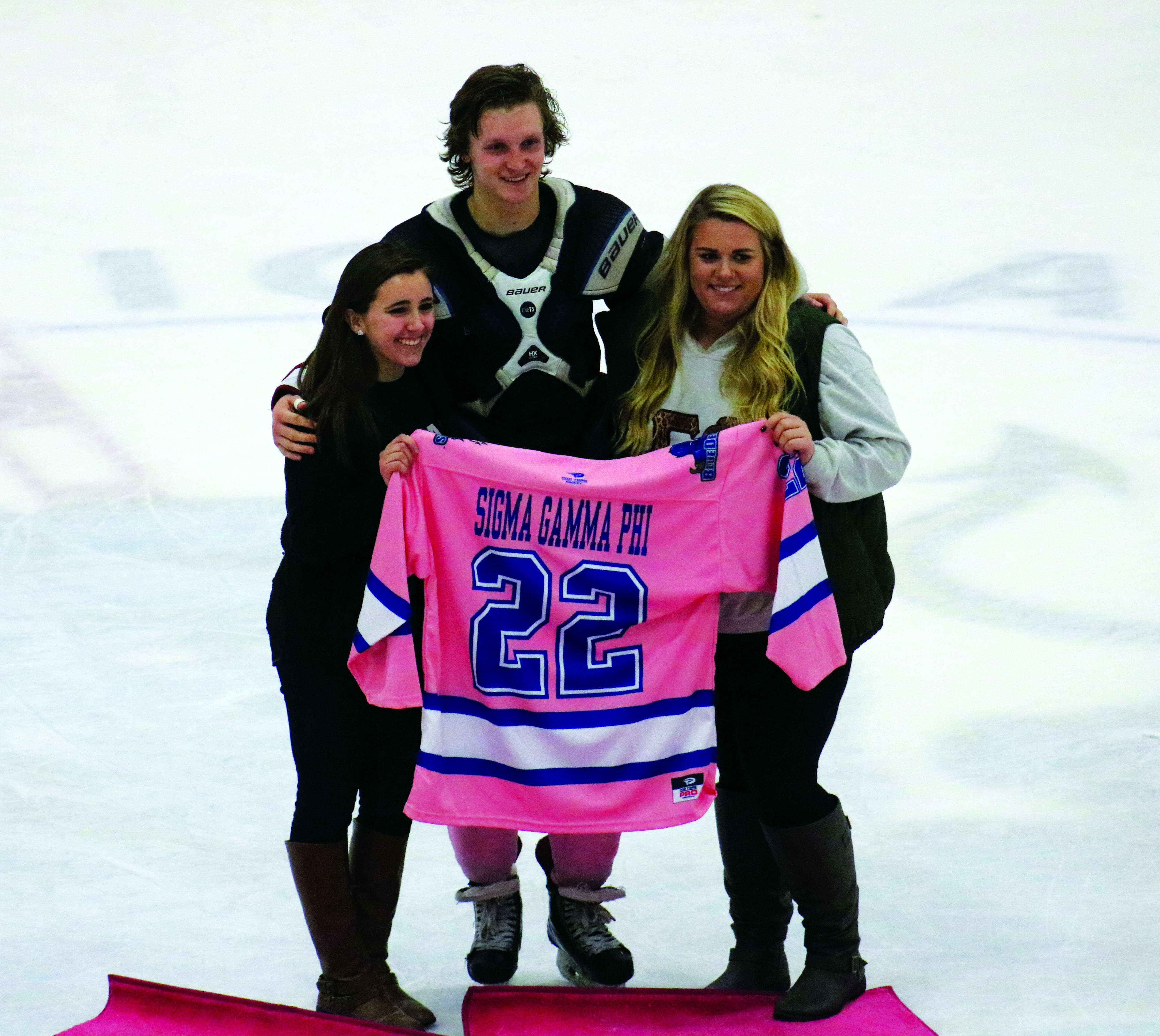 Allison Plunkett (left) and Sarah Doherty (right) accept Jimmy Morgan’s (middle) Pink the Rink jersey for Sigma Gamma Phi.Photo by Meghan Guattery